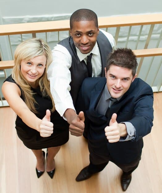 A group of business executives smiling and shaking hands, symbolizing increased business confidence and profitability as a result of the lower tax rate. The image should have a bright and optimistic tone.