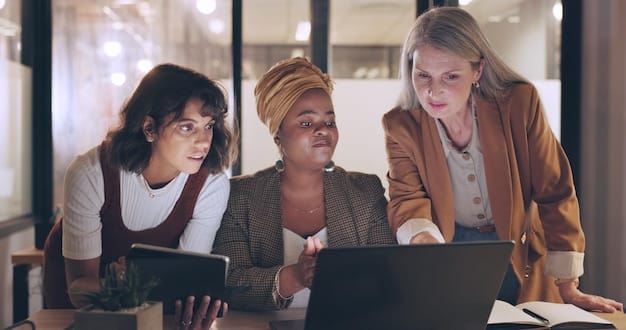 A diverse team of professionals collaborating around a table, discussing data insights and strategies using laptops and tablets, emphasizing teamwork and data-driven decision-making.