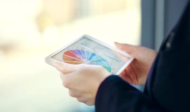 A human resources professional reviewing data on a tablet, with various graphs and charts on a digital interface in the background, illustrating the use of technology in HR.
