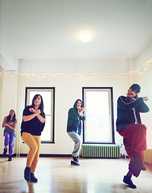 A group of young Americans of various ethnic backgrounds collaboratively practicing K-Pop choreography in a studio, showcasing diversity and shared passion.