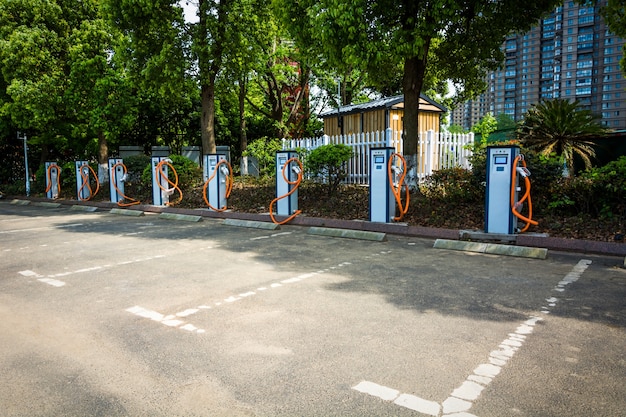 A photo of a charging station being installed in a public parking lot. Workers are setting up the charging unit, with city buildings in the background.