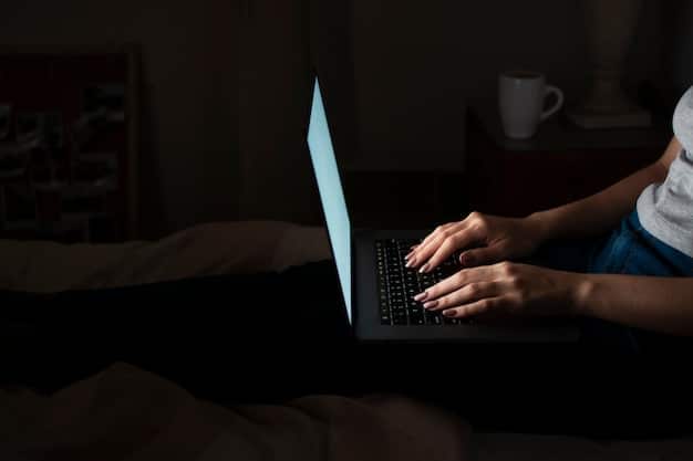 A close-up of a hand typing on a laptop in a dimly lit room, with lines of code faintly visible on the screen. The focus is on the intensity and stealth of cybercriminals at work, emphasizing the need for constant vigilance against cybersecurity threats.