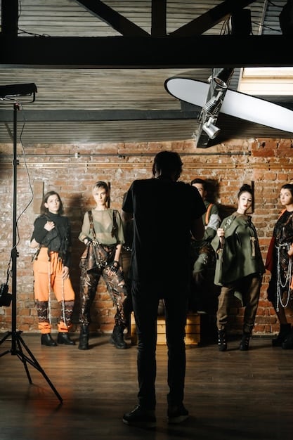 A behind-the-scenes shot of a virtual production set, showing actors performing in front of large LED screens displaying a detailed virtual environment. Key crew members are visible, focusing on monitors and adjusting equipment. This image reflects the immersive experience of virtual production.