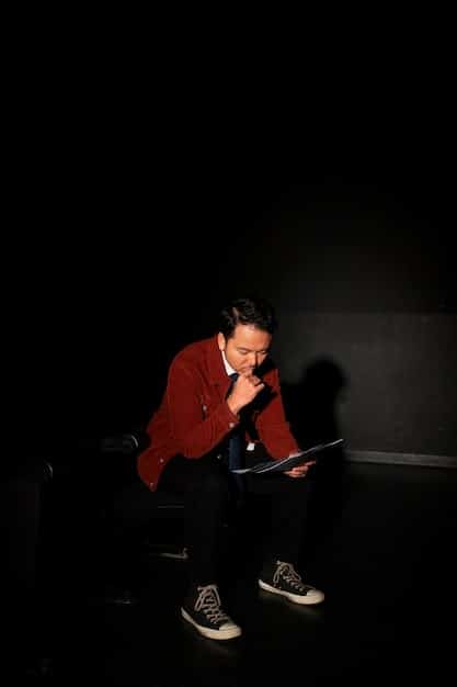 The image depicts a person sitting in a darkened recording studio, bathed in the soft glow of a mixing console. The setting feels intimate and somewhat solitary, highlighting the effort and introspection required to reinvent oneself. This conveys the dedication a star needs when aiming for 